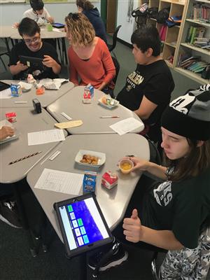 Teacher and three students eating lunch and communicating with iPad with communication app 